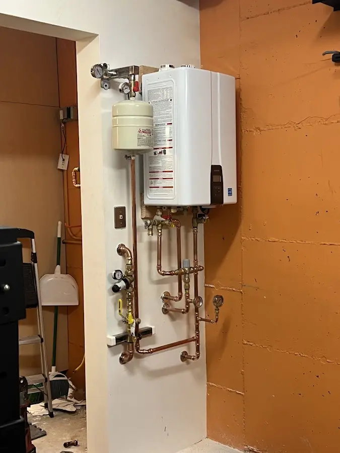 Plumbing technician inspecting water heater connections in Hopkinton